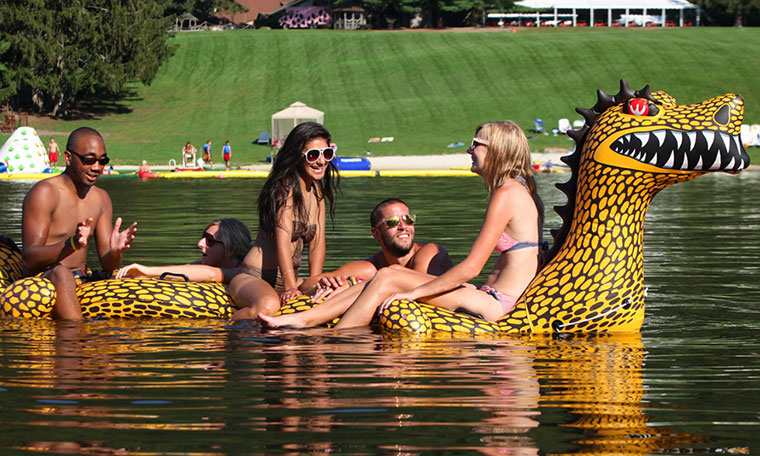 Group of friends floating on dragon shape float on lake.