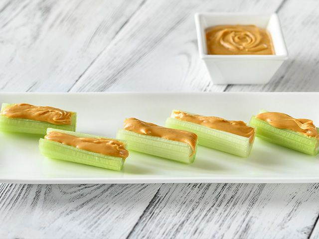 Tray of peanut butter on celery snack.