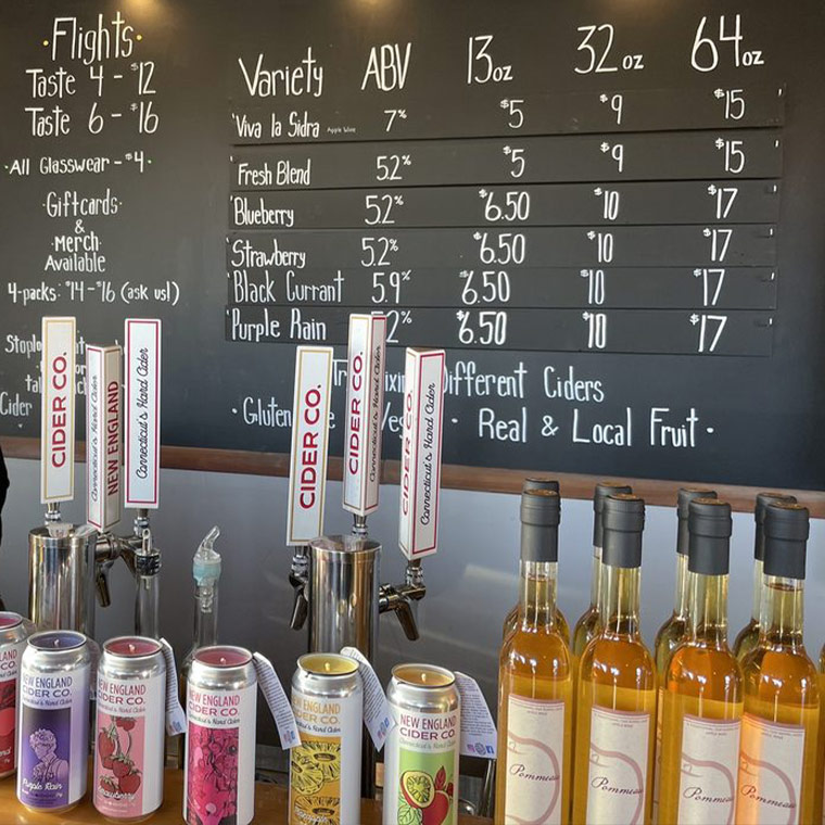 An image of the New England Cider Company taproom, showcasing the cozy wooden bar and selection of cider offerings