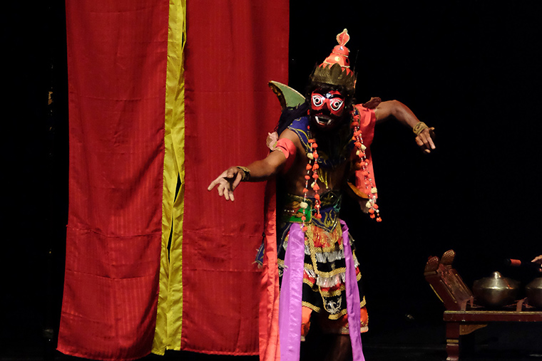 Black performing artist wearing cultural costume and mask