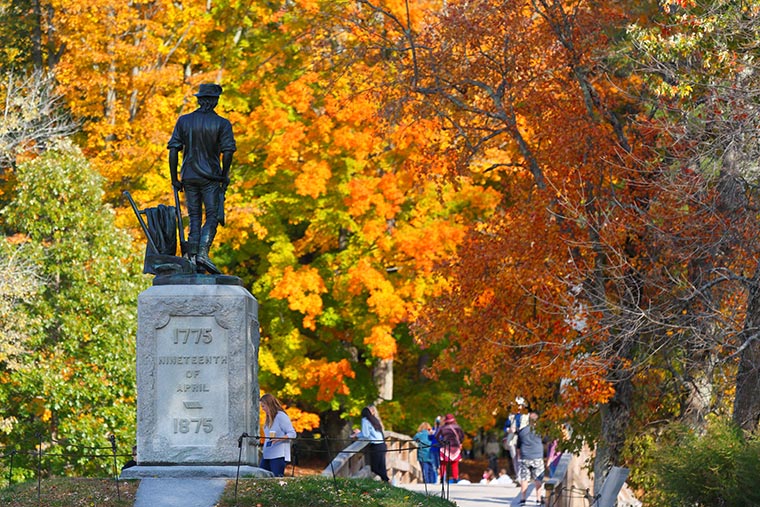 The Minute Man statue and North Bridge at Minute Man National Historic Park with fall foliage as background, Concord Massachusetts.