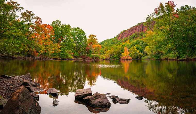 New Haven East Rock Park rocky mountain reflecting off pond during a autumn day.