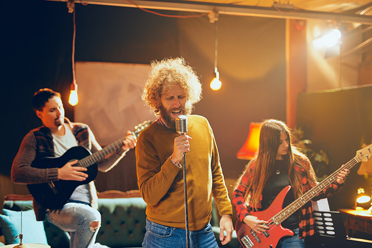 Indie band performing on small stage: male singer, female bass guitarist, and male guitarist.